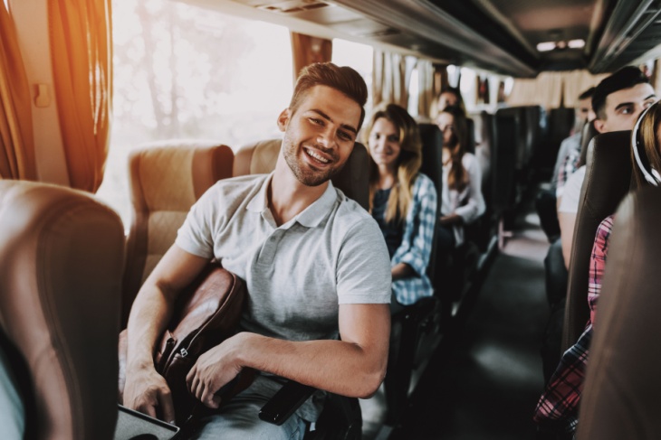 Man on bus holding backpack
