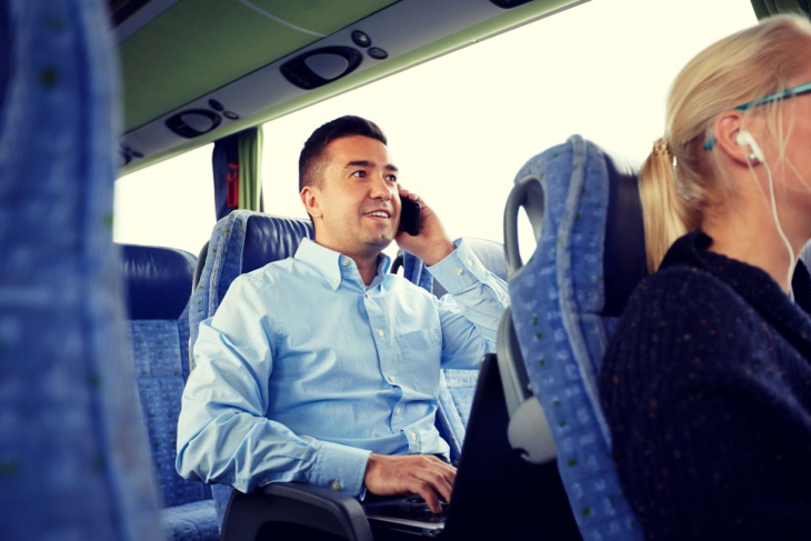 Man sitting on bus talking on a cell phone