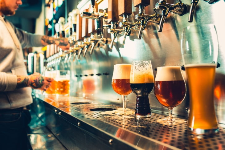 Different size glasses of beer sit on a counter